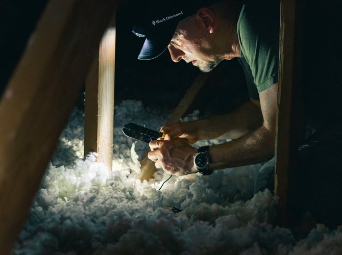 Man working on insulation in a dark attic