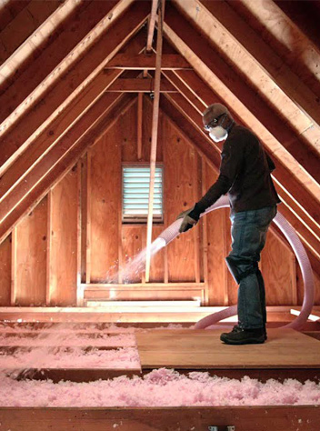 Person blowing in insulation in an attic